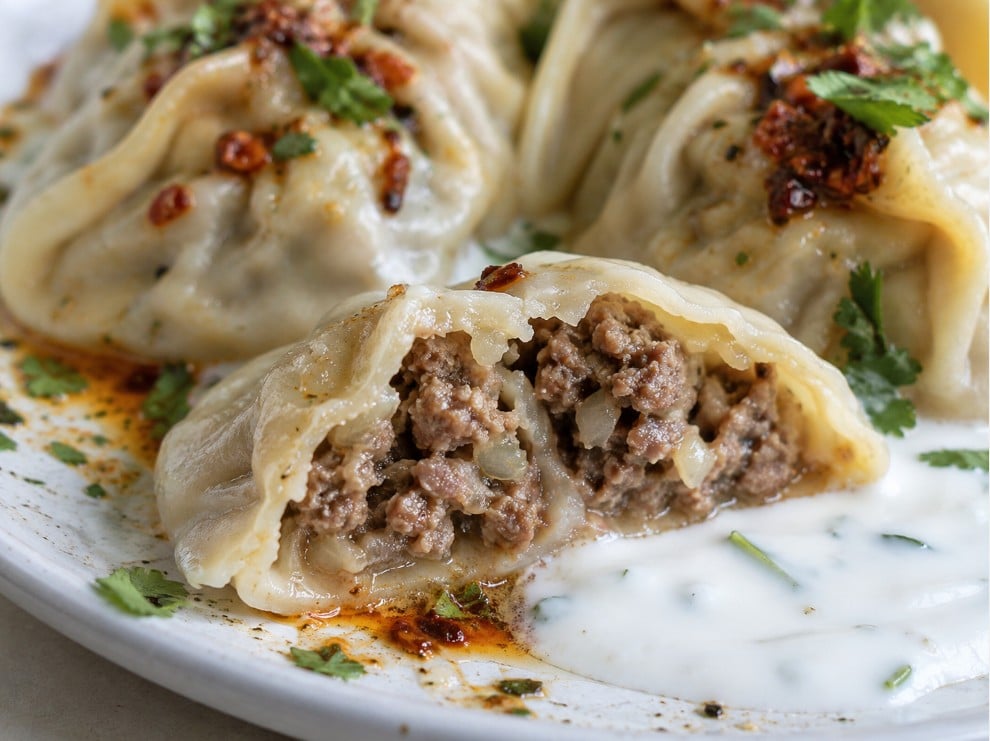 Afghan mantu cut open to show minced meat and onion filling