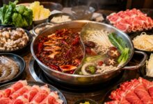 Steaming divided hot pot with beef, lamb, shrimp, tofu, mushrooms, greens and noodles at a modern restaurant