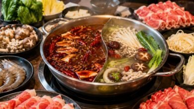 Steaming divided hot pot with beef, lamb, shrimp, tofu, mushrooms, greens and noodles at a modern restaurant
