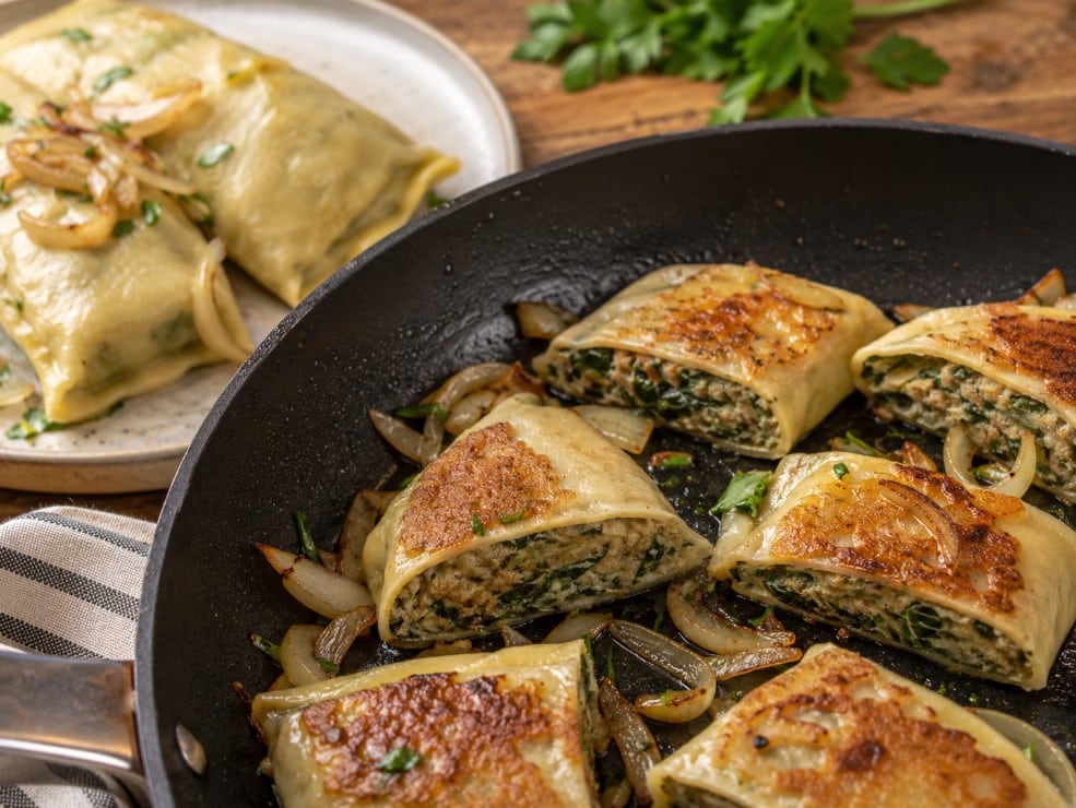 Cooked Maultaschen sliced and pan-fried with browned cut surfaces and golden onions