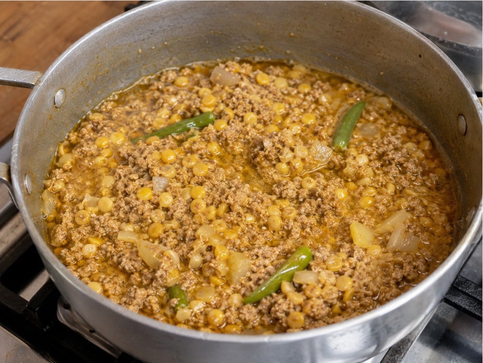 Meat and lentils cooking together with aromatics and spices for shami kebab