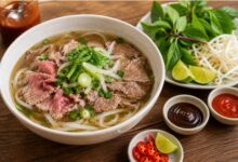 Vietnamese pho with aromatic broth, flat rice noodles, sliced beef, scallions and fresh herbs